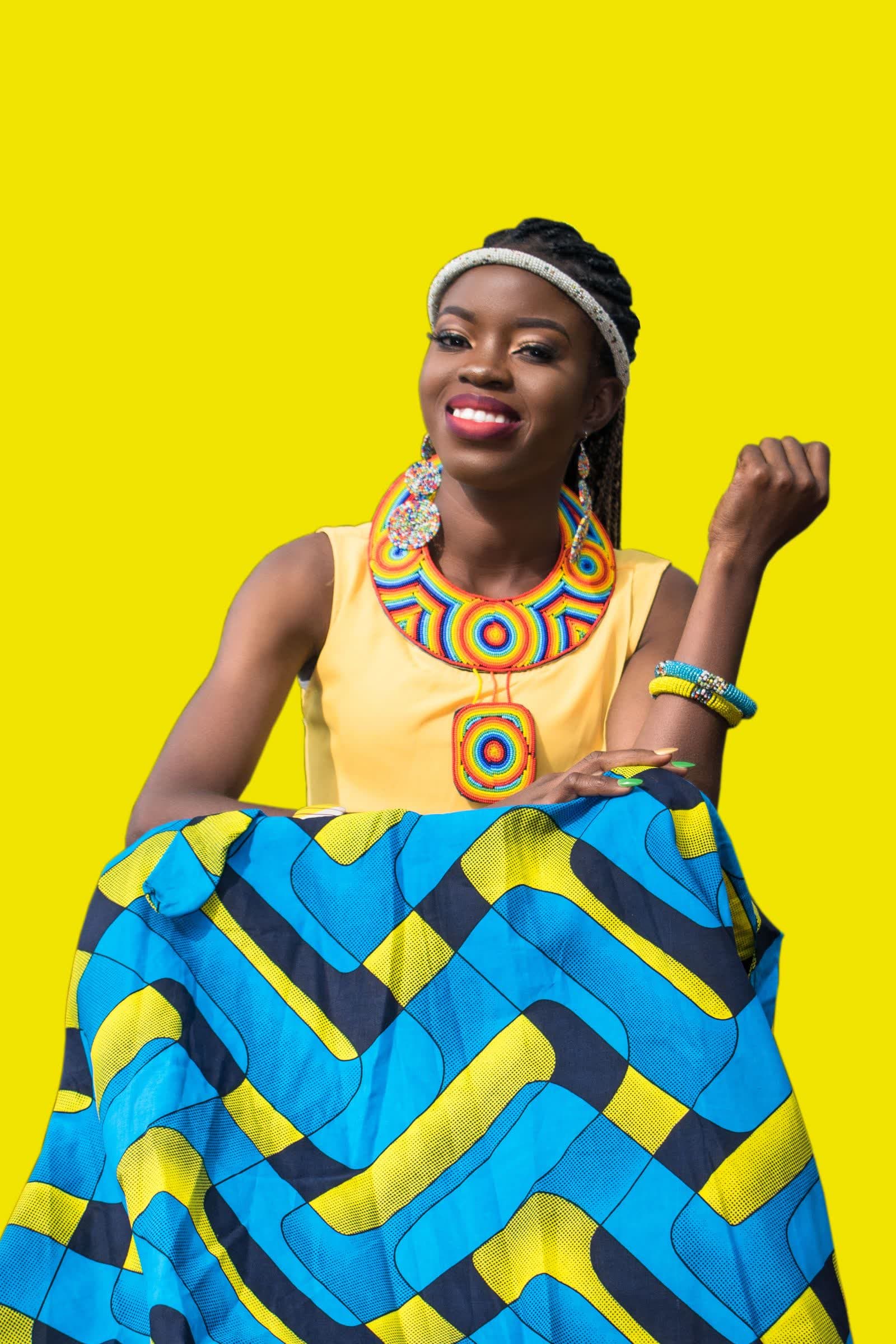 A creator in beadwork against a yellow backdrop