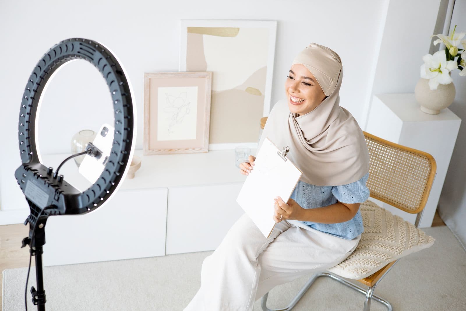 A creator smiling while planning a lesson in front of a ring light